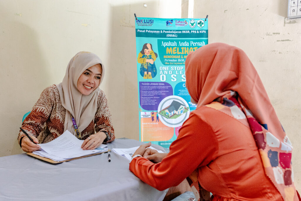 A woman staff of the One Stop Service and Learning (OSS&L) room at Kelobak Integrated Health Centre in Bengkulu explaining things to a patient.